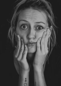 Black and white picture of a blonde woman touching her cheeks